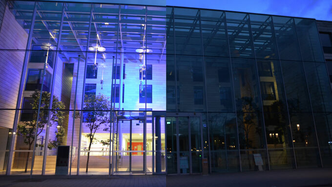 Dienstgebäude der Bezirksregierung Münster, bei dem die hälfte des Bildes in blau erstrahlt und die andere dunkel ist